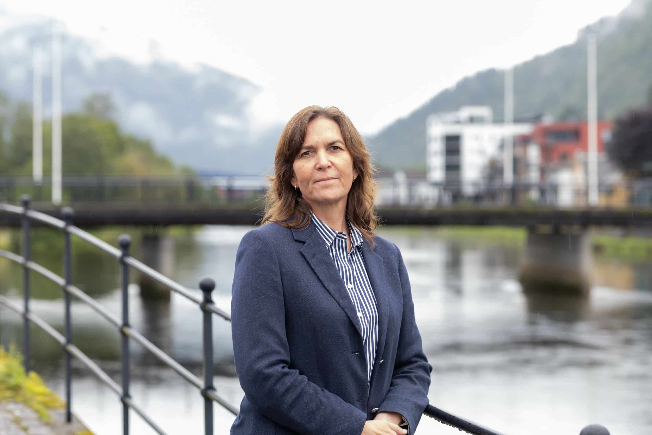 Bilde av Anya Therese Markhus, seniorr&aring;dgivar i Lotteritilsynet. Hun st&aring;r ute ved elven i F&oslash;rde, i en m&oslash;rk dressjakke og en stripete skjorte.